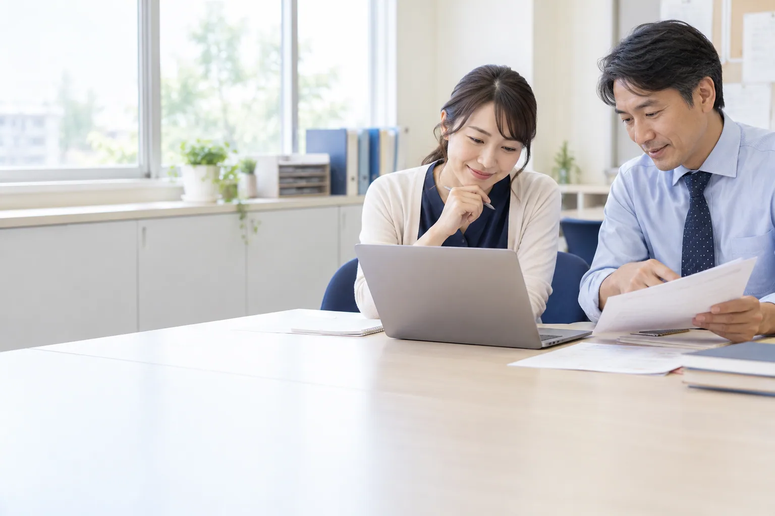 AI生成イメージ：ノートパソコンと資料を使って研修する教員の場面